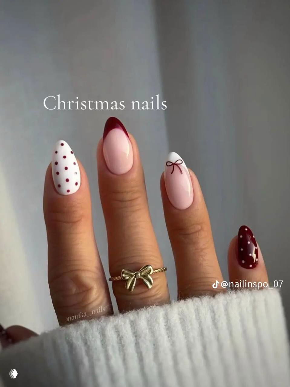 Рука с вытянутыми овальными ногтями, сочетание нюдовой базы и бордовой улыбки френча, на фото текстовый отпечаток "Christmas nails" и тёплый фон.