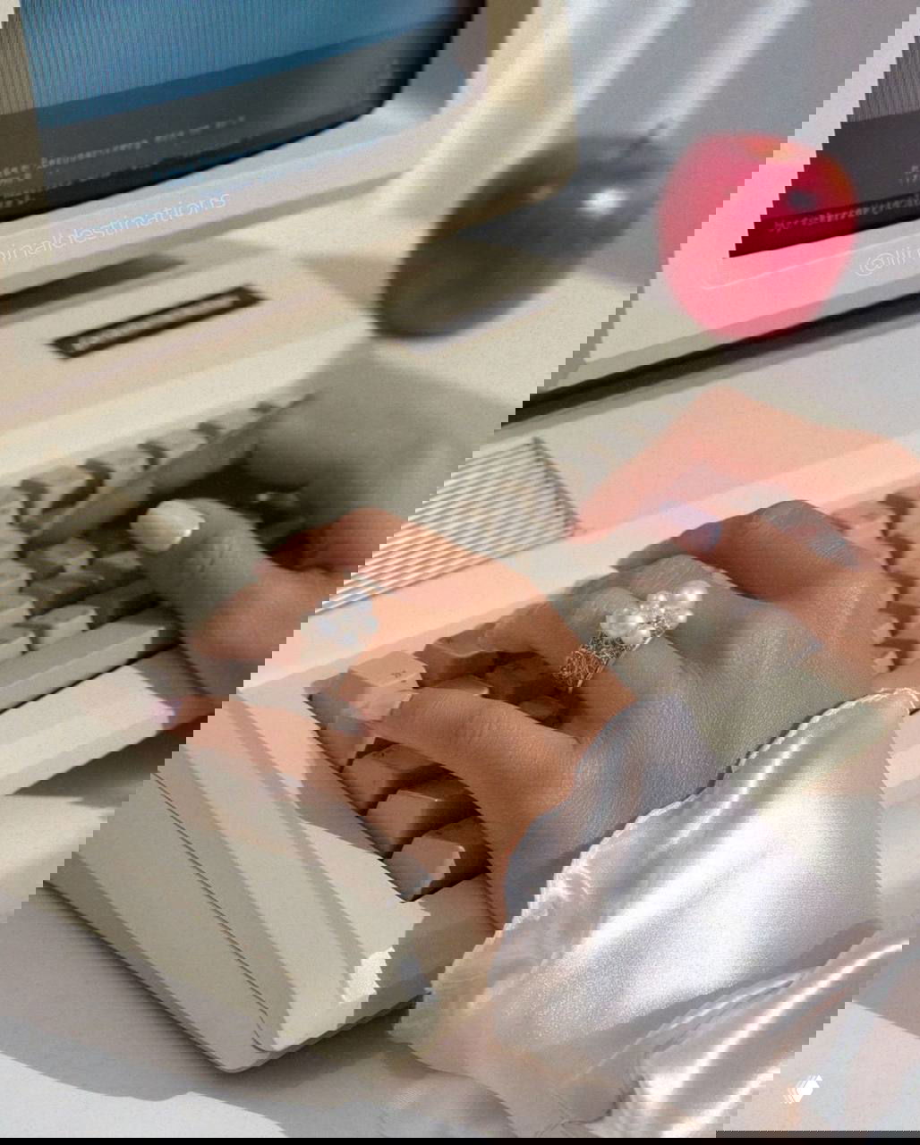 Руки с жемчужным кольцом печатают на старом компьютере; сочетание женственности и техно‑винтажа для эстетики glamoratti.