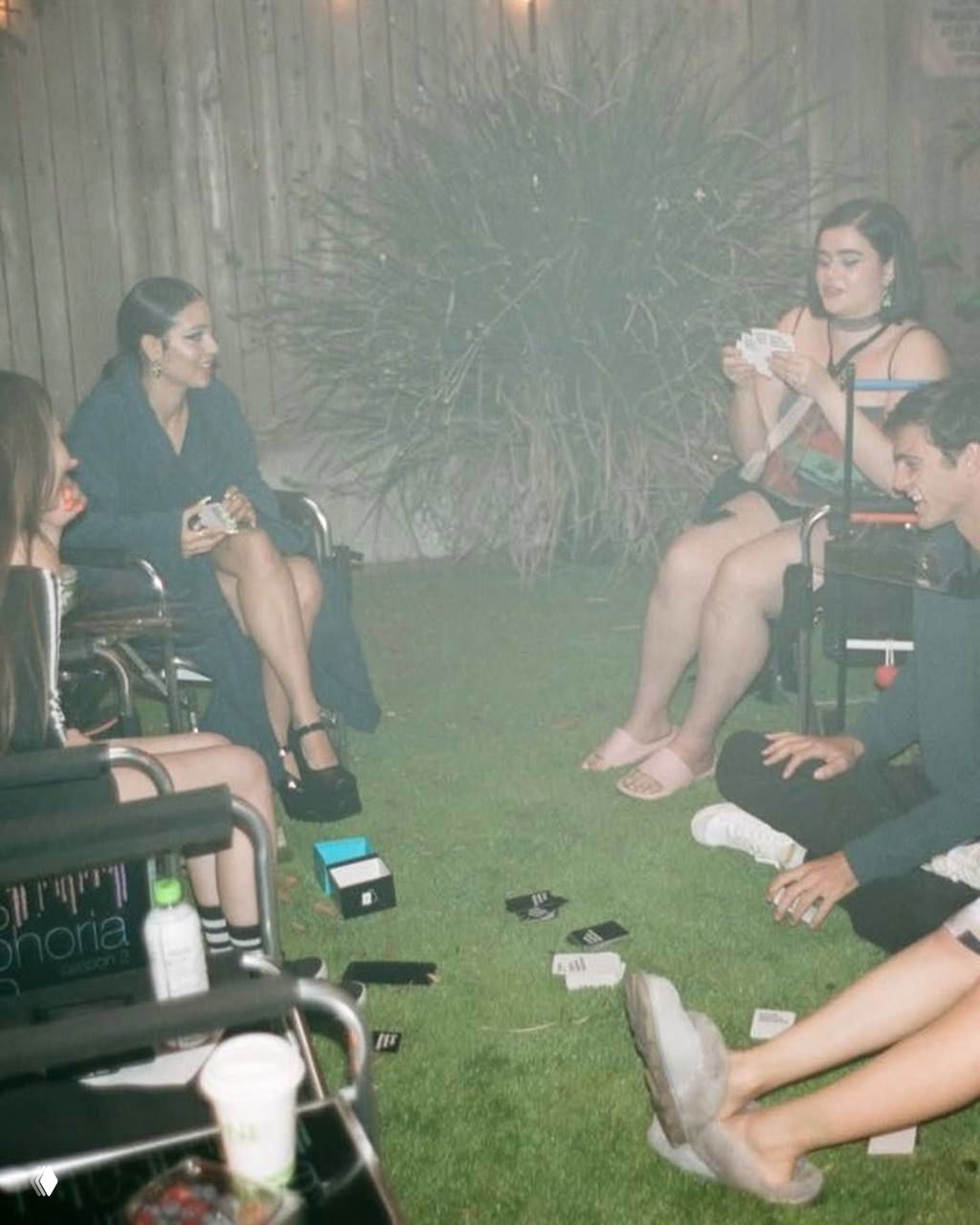 Неформальная ночная сцена бэкстейджа: актрисы сидят во дворе и играют в карты, видно реквизит и разговоры между дублями.