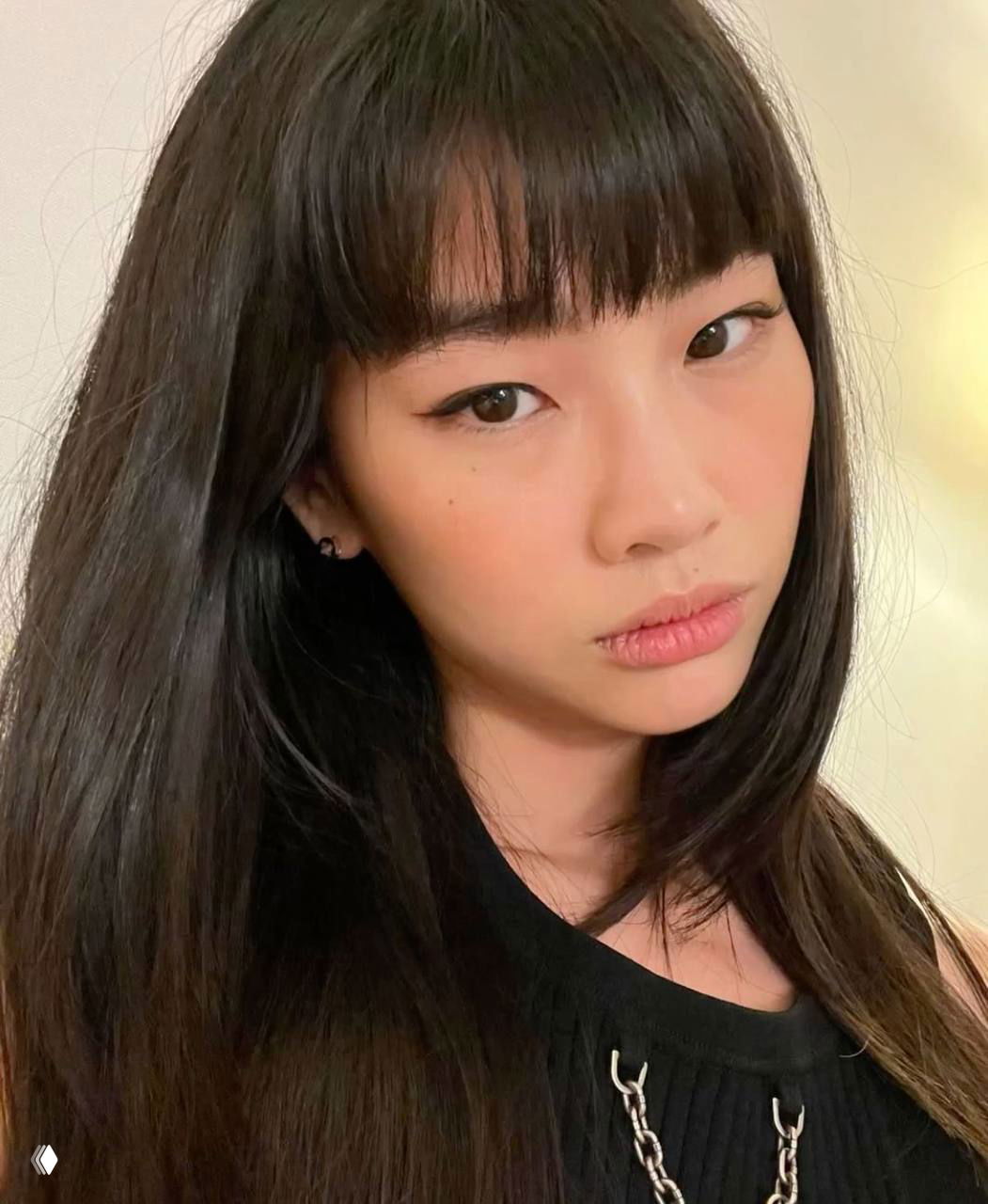 Крупный план лица молодой женщины с распущенными волосами и лёгким макияжем; видна гладкая текстура кожи и блеск волос крупным планом.