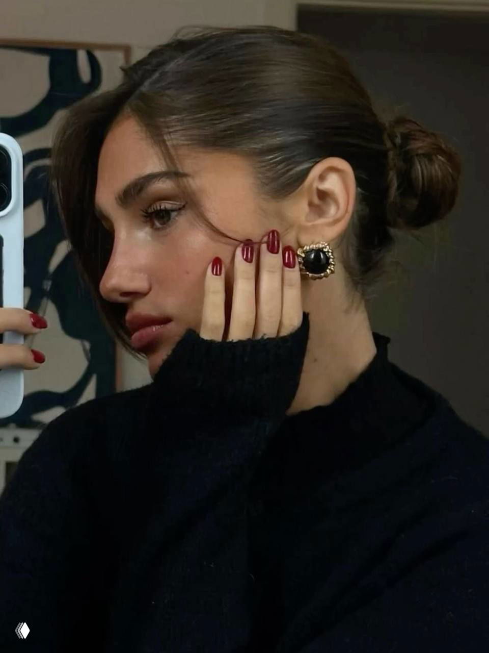 Селфи девушки с аккуратным бордовым маникюром, собранными волосами и заметной винтажной серьгой; контраст тёплого макияжа и глубокого оттенка лака.