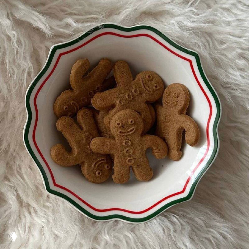 Керамическая миска с имбирными пряниками на пушистом фоне; фигурки с простыми улыбками, тёплая домашняя подача и праздничный мотив в кадре.
