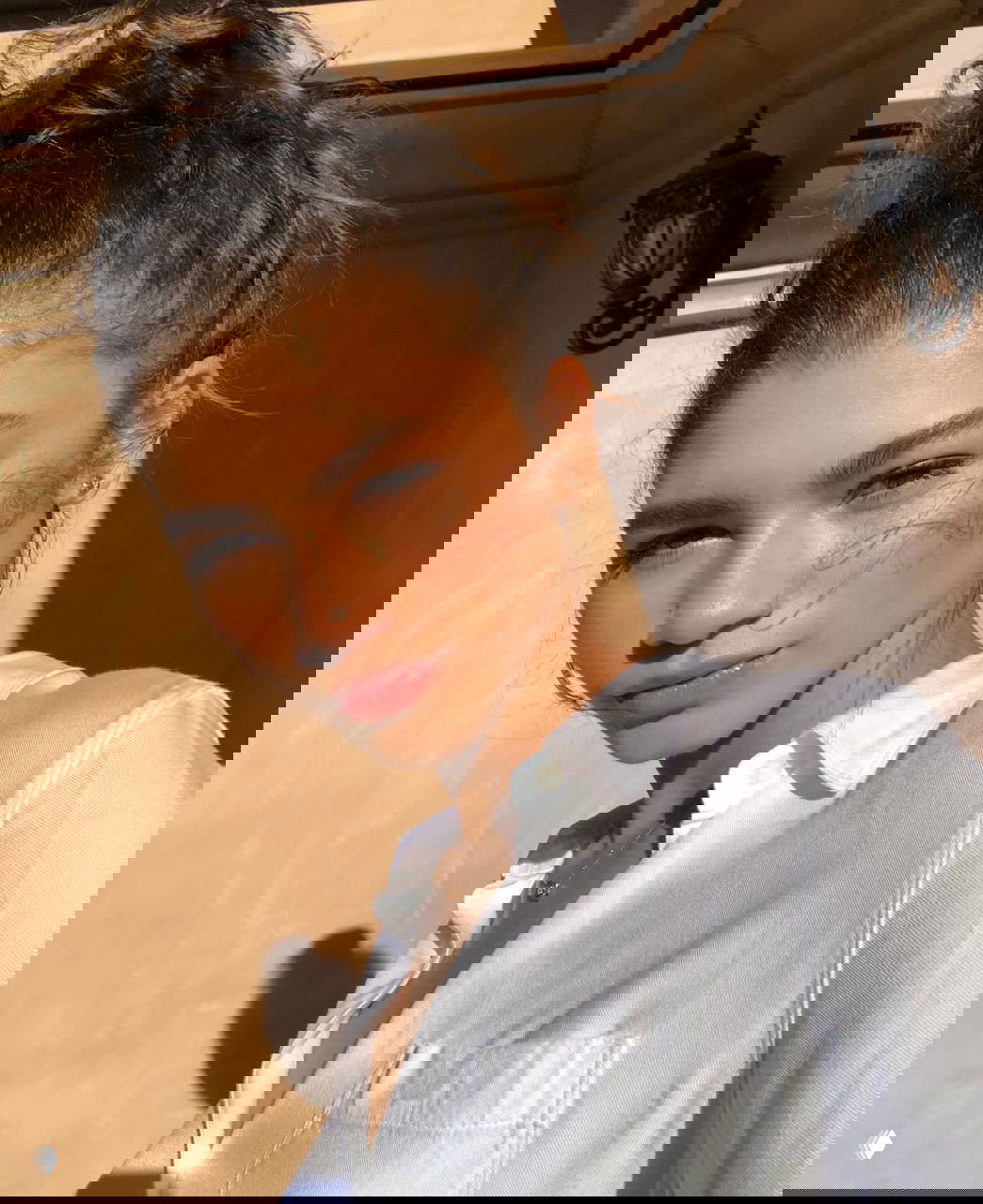 Солнечный портрет молодой женщины в мягком естественном макияже: сияющая кожа, лёгкие румяна и нейтральные тона на тёплом фоне, эстетичный кадр.