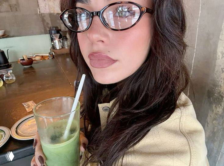 Крупный план лица с аккуратными коричневыми очками-оправой: минималистичный макияж и мягкий свет подчёркивают форму оправы и естественный вид.