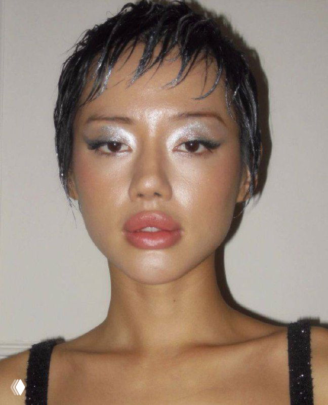 Портрет модели с ярким серебристым макияжем глаз и нейтральными губами; прическа короткая, взгляд в камеру, акцент на текстуре кожи и тенях.