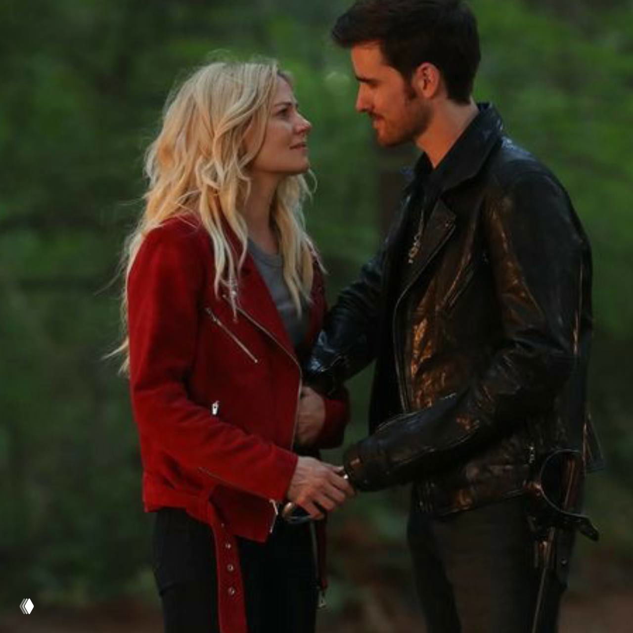 Пара в лесу: Эмма и Киллиан смотрят друг на друга на зелёном фоне, повседневная одежда и рукопожатие как символ взаимной поддержки.