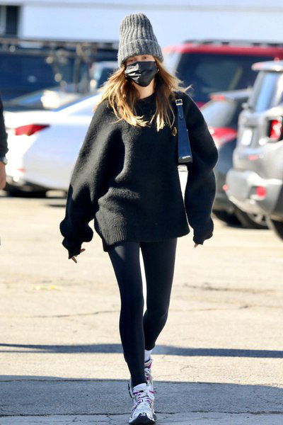 Женщина в объёмной вязаной шапке-бини и маске, спортивно-повседневный образ на парковке — папарацци-снимок вне событий.