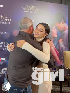 Ханде Эрчел в светлом платье тепло обнимает одного из братьев‑продюсеров на пресс‑подходе фильма «Два мира, одно желание» в Москве, на фоне постера фильма.