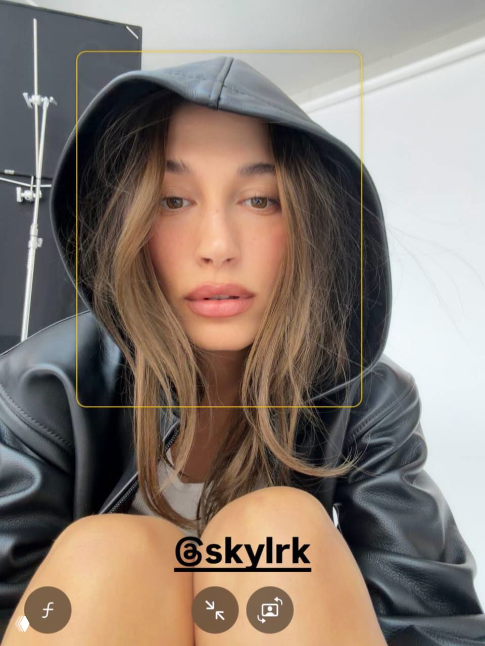 Портретное селфи Хейли Бибер в худи и вещах бренда SKYLRK: крупный план лица, естественный макияж и поза в студийной обстановке.