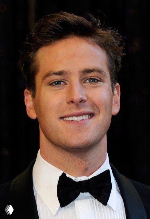 Крупный план лица мужчины в праздничной одежде: фотопортрет с улыбкой на фоне события, формальная одежда и светская обстановка.