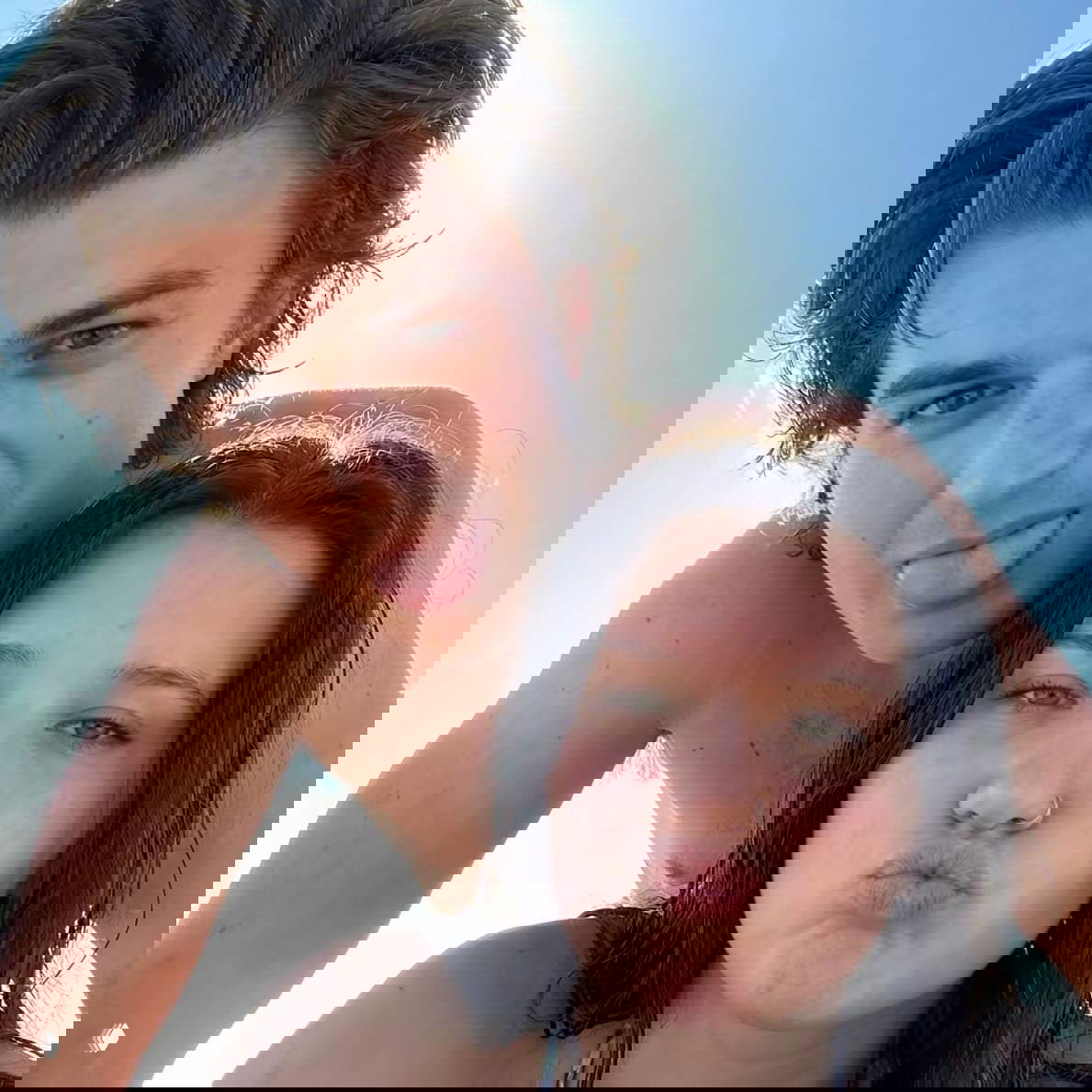 Крупный план мужчины и женщины на улице или пляже: они рядом, улыбки и тесная поза создают иллюзию романтической пары на прогулке.