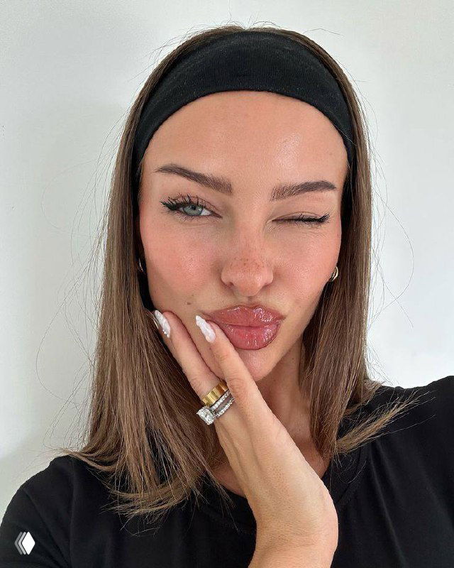 Крупный план лица женщины с глянцевой помадой и естественной кожей, лёгкий лавандовый румянец и аккуратные ресницы