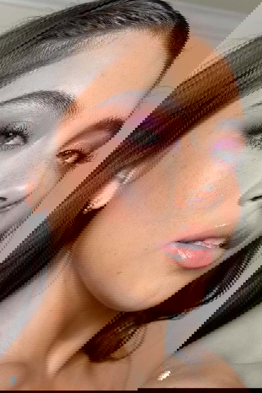 Портрет девушки крупным планом с фиолетовыми тенями на веках, подчёркнутыми ресницами и сияющей кожей — макро-кадр макияжа.