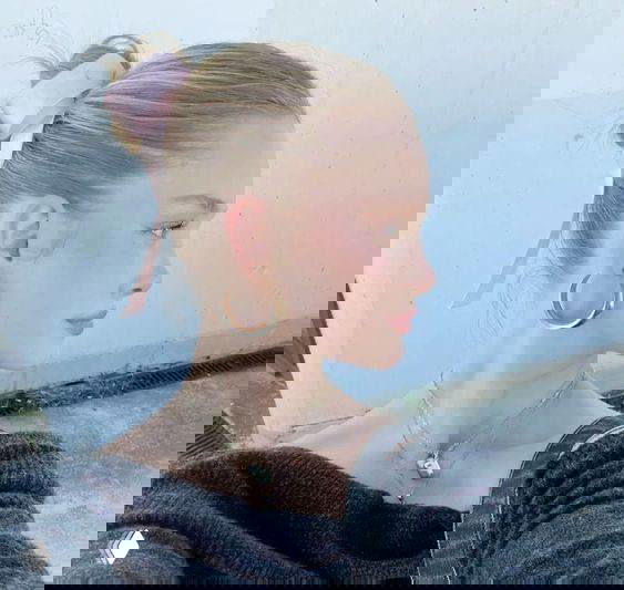 Мини-фото в профиль молодой женщины с высоким хвостом и лёгким макияжем в пастельных оттенках на нейтральном фоне