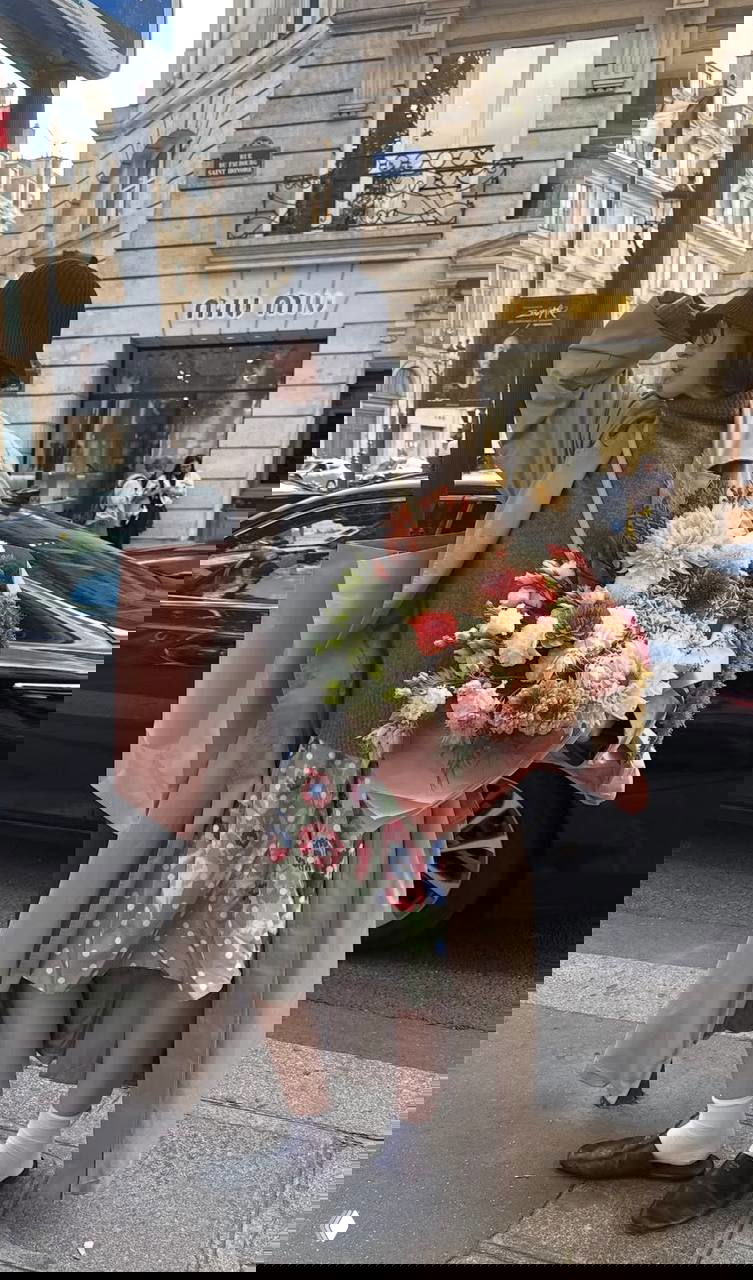 Лиза в длинном тренче на городском фоне с большой букетной композицией, гороховая юбка, шляпа клош и сочетание пальто и аксессуаров осенью.