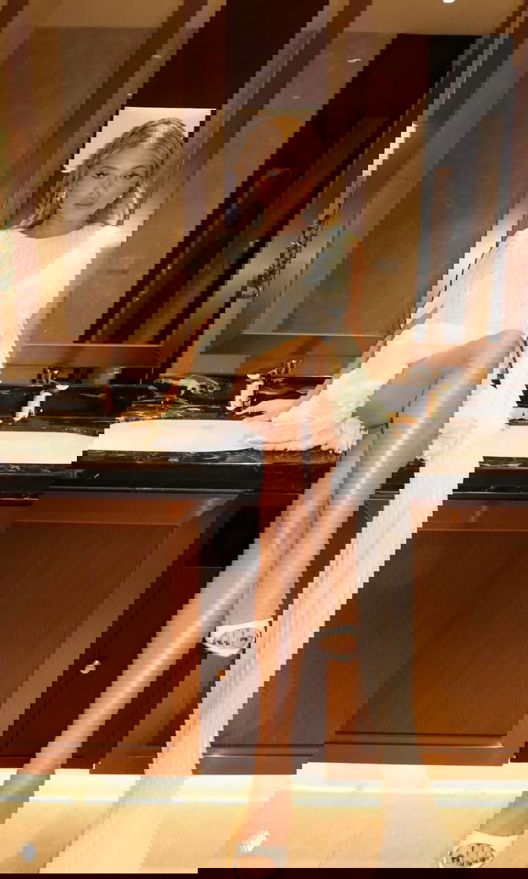 Катины снимки в светлом драпированном платье; актовая поза на умывальнике, видны молочные мюли на каблуке и вечерний интерьер номера.