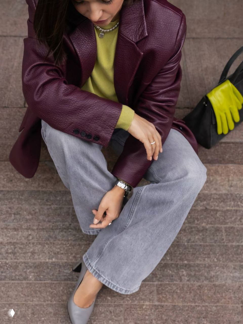 Сидящая модель в бордовом кожаном пиджаке и салатовой водолазке, детализация образа и акцент на контрасте зелёного и бордового для осени.