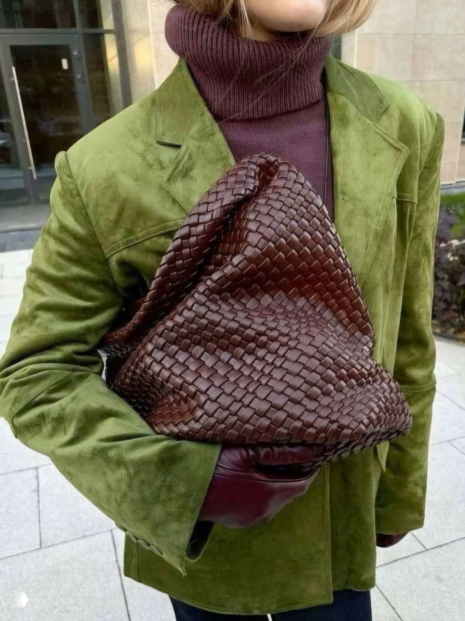 Крупный план: плетёная бордовая сумка на фоне зелёного бархатного жакета и бордовой водолазки — текстуры усиливают эффект сочетания цветов.