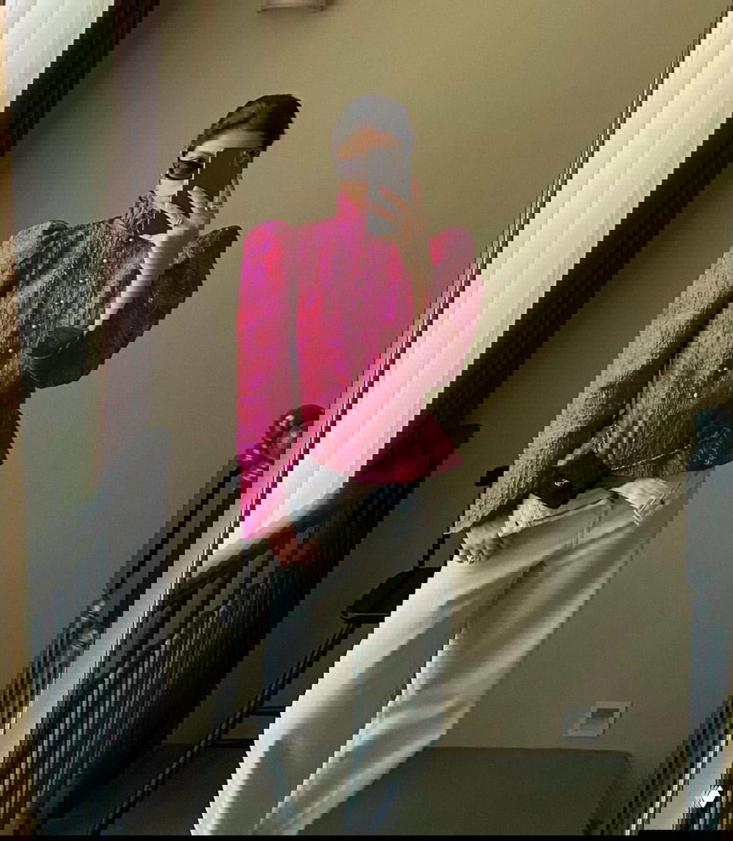 Селфи в зеркале: яркая малиновая жаккардовая блуза с объёмными плечами и рядом декоративных пуговиц, образ в домашней или отельной обстановке.