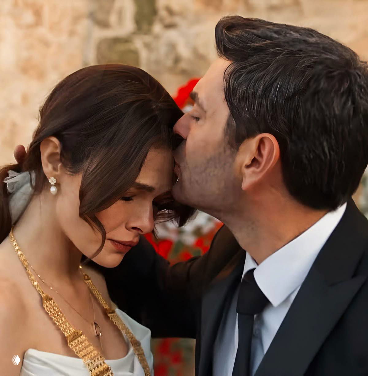Крупный кадр: Джихан целует лоб Альи, она с грустным выражением лица, украшения и костюм указывают на торжественный момент.