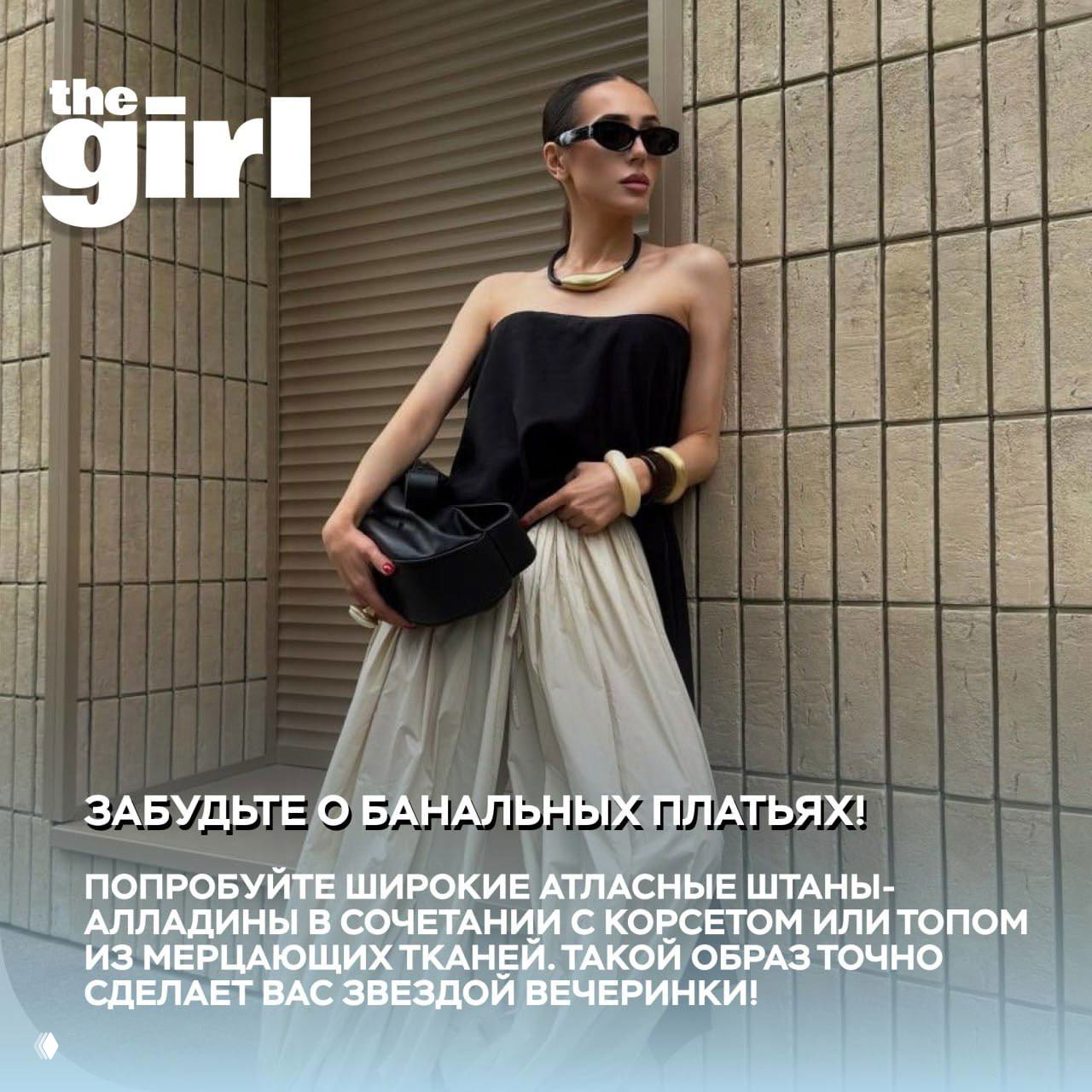 Модель в черном топе и широких сатиновых штанах-алладинах у стены; пример вечернего образа с акцентными брюками.