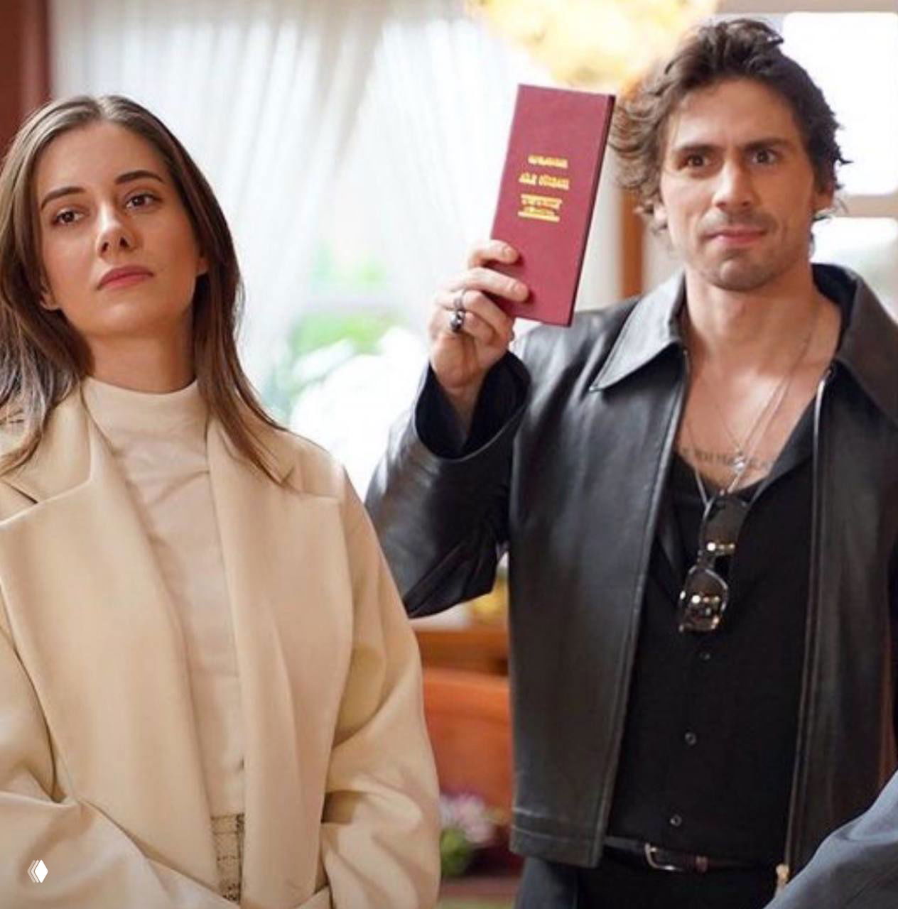 Кадр из эпизода турецкого сериала: пара стоит в интерьере, герой держит документ, в сцене видна напряжённая динамика между персонажами.