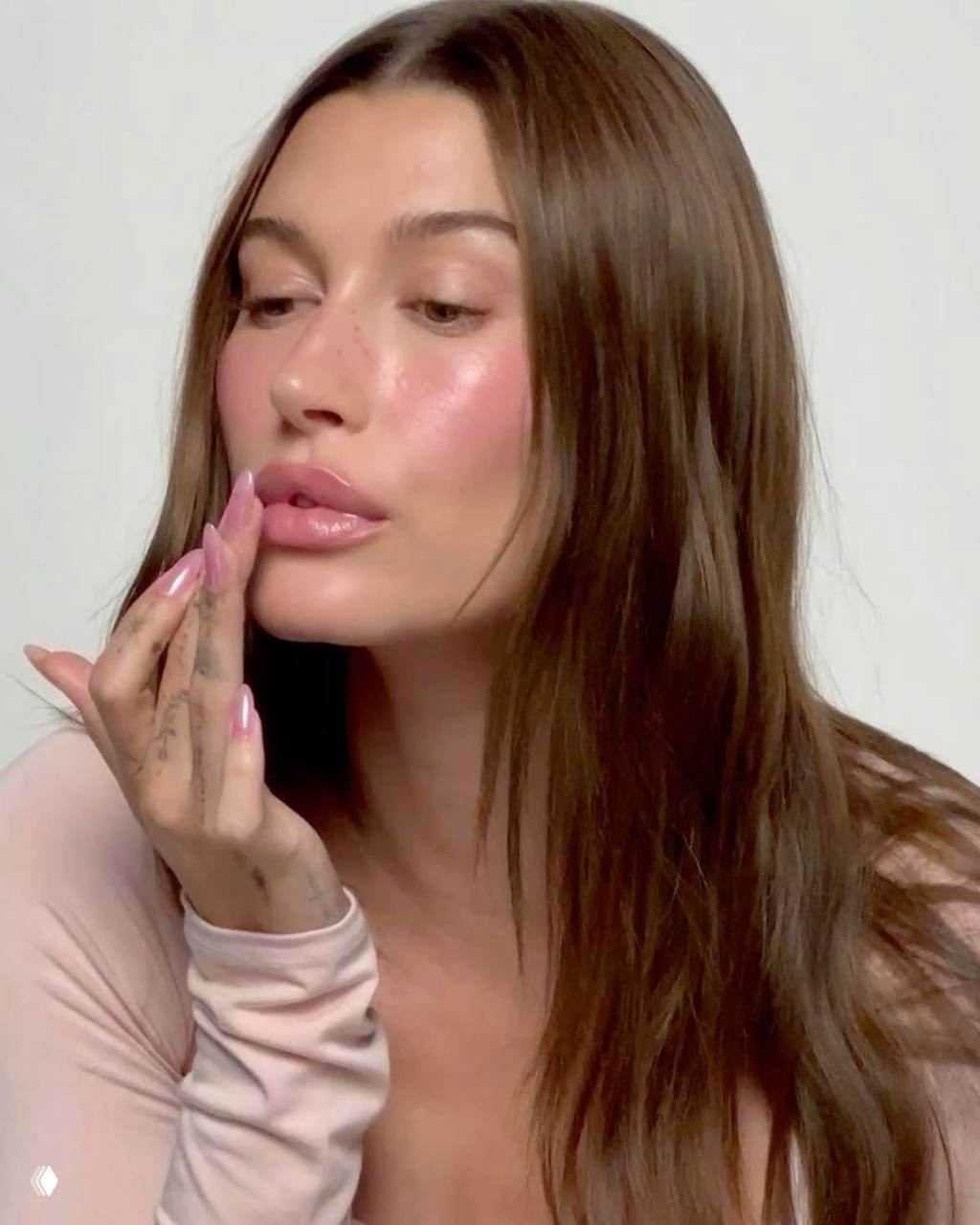 Портрет женщины с акцентными глянцевыми губами, заметным румянцем и сияющей кожей — нежный бьюти-образ в мягкой пастельной гамме для вдохновения.