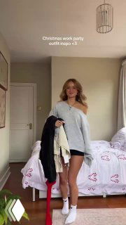 Малин в светлой спальне держит несколько вещей в руках — подборка новогодних образов на фоне кровати с праздничным постельным бельём.