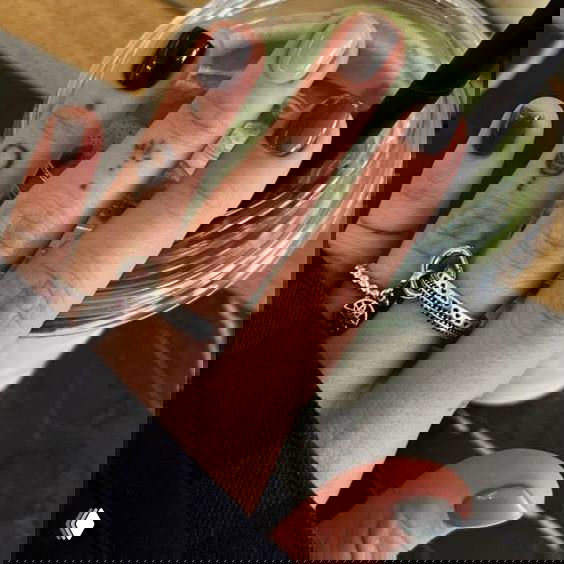 Крупный план руки с мелкими тату и кольцами — аксессуары и маникюр, которые дополнительно подчёркивают альтернативный стиль образа Фрэнки для Хэллоуина.