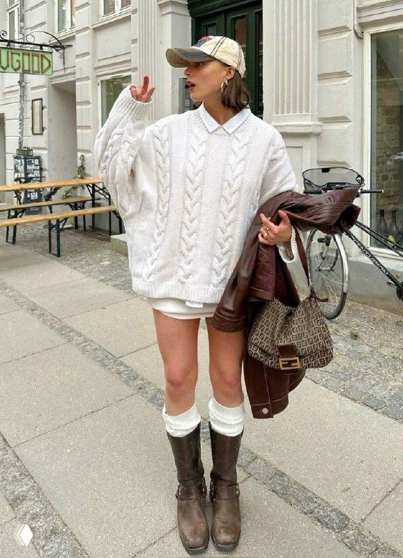 Стрит-лук: белый вязаный свитер, короткая юбка и темные сапоги с белыми завернутыми носками, создающими эффект имитации гольфов в образе.