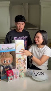 Двое людей за столом распаковывают коробочки‑surprise: на столе видны игрушки, упаковки, брендированная коробка и продукты, похожие на Dove.