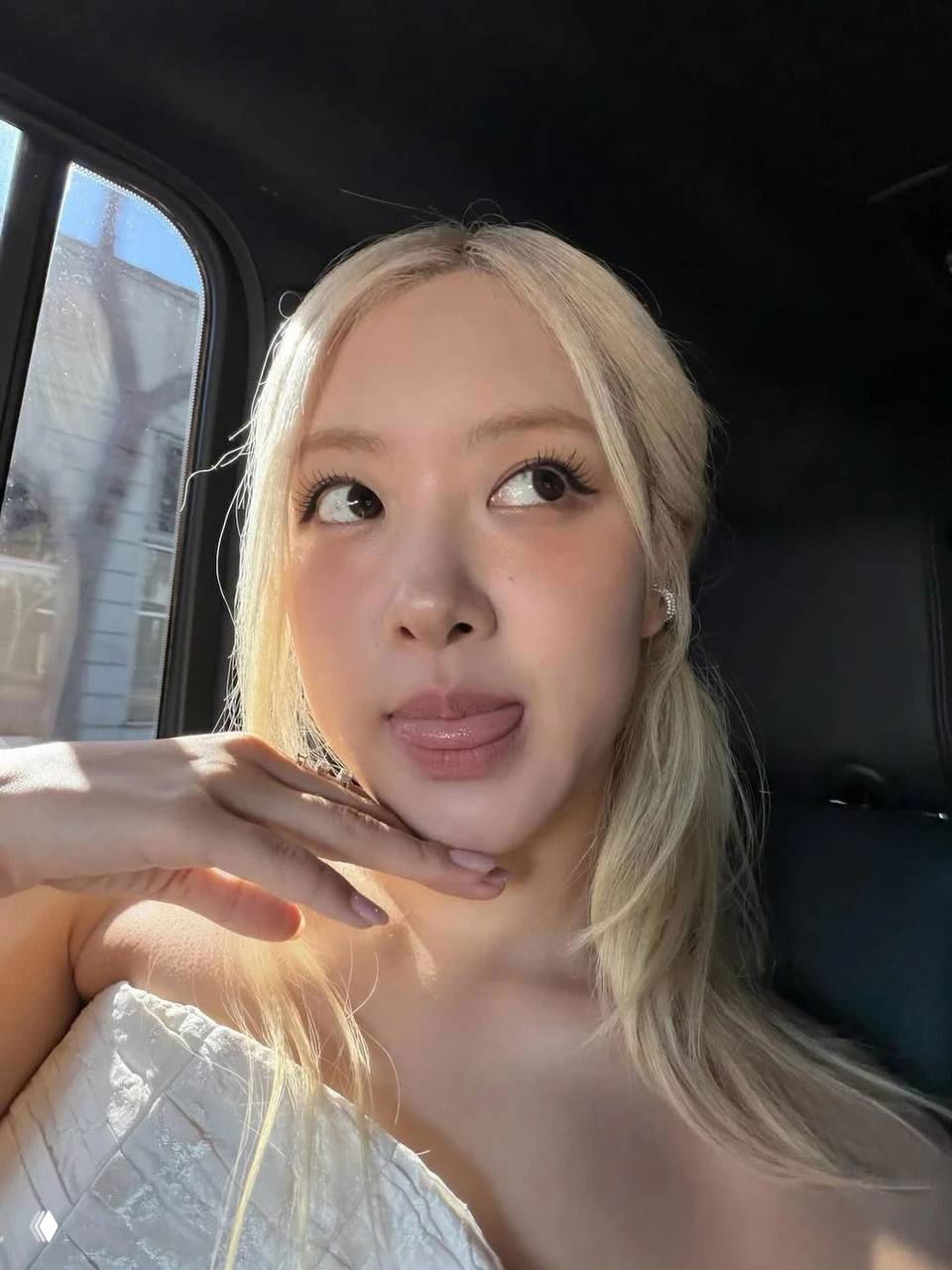 Крупный план молодой женщины со светлыми волосами в салоне автомобиля; макияж с небольшой чёрной стрелкой на верхнем веке и мягким дневным светом.