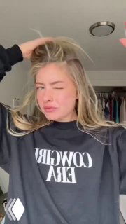 Кадр девушки в уютном свитшоте, расчёсывающей и улучшающей причёску руками, демонстрация текстуры волос и подготовки к простому образу.