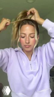 Фронтальный кадр девушки, разделяющей пряди у лица и фиксирующей их заколкой или лентой, отображение лёгкой, непринуждённой школьной укладки.