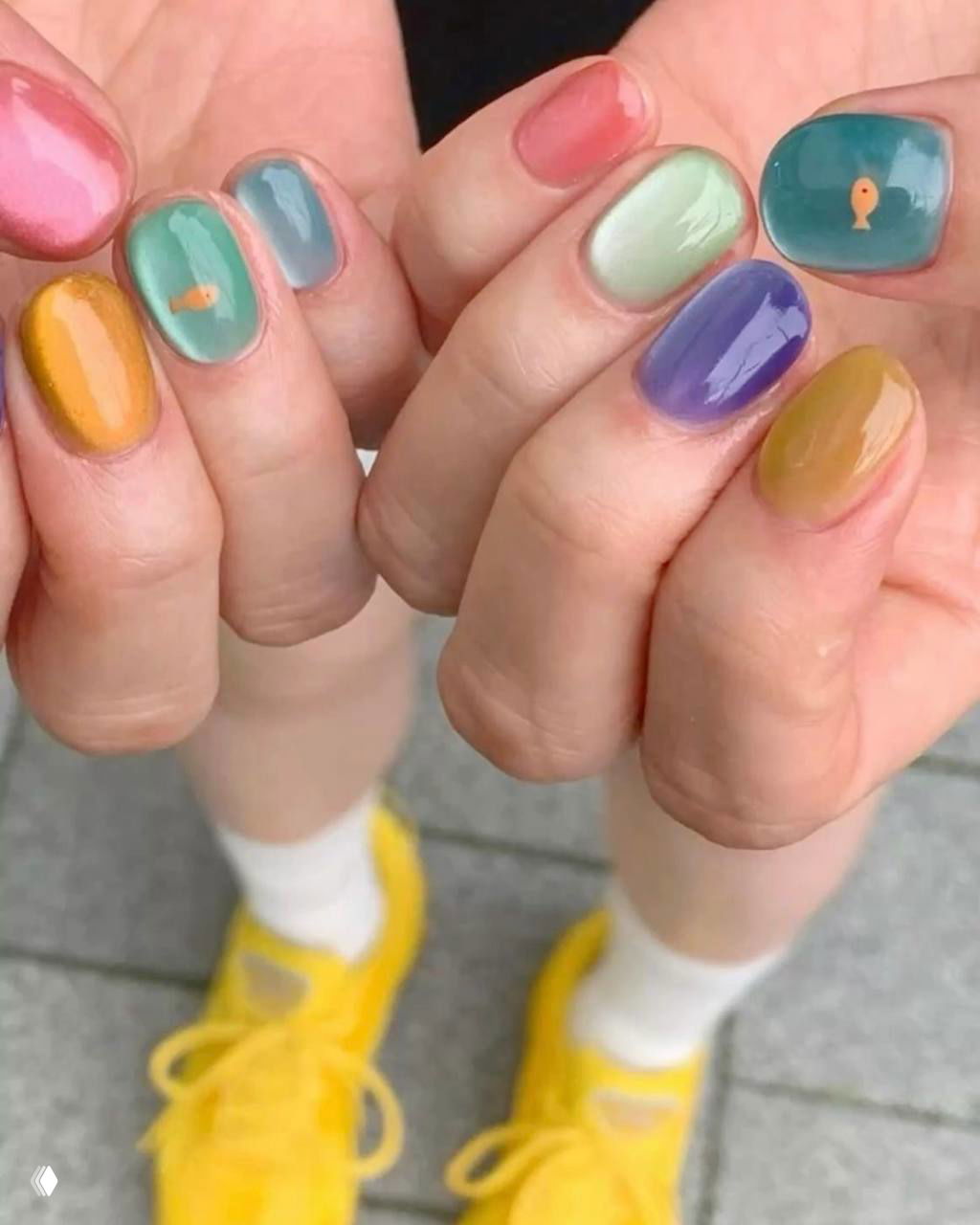 Крупный план глянцевого мармеладного нейл-арта в пастельных оттенках: прозрачная желейная текстура, мягкие градиенты и миниатюрные декоры на ногтях.