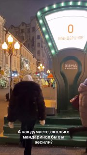 Ночная фотография инсталляции на Арбате: большая весовая установка с оформлением и надписью про мандарины, прохожие рядом и украшенные фонари улицы.