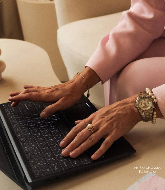 Руки взрослых людей печатают на клавиатуре рядом с согнутыми ногами, видны кольца и браслеты; художественный глитч-эффект.