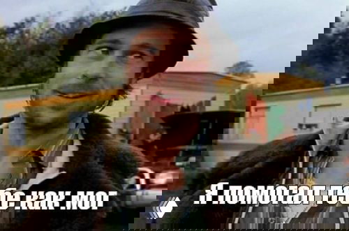 Мем с мужчиной в шляпе и лёгкой ироничной улыбкой на фоне жилого трейлера и зелёного пейзажа; подпись внизу: «я помогал тебе как мог»