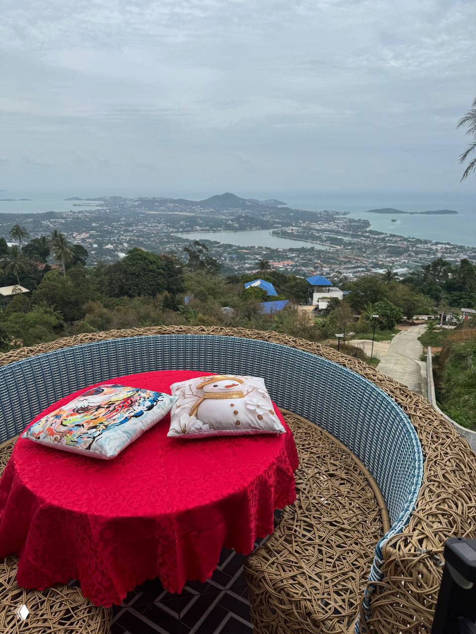 Панорамный вид с террасы Highland Paradise (Чавенг хил): на переднем плане плетёное «гнездо» с красной скатертью и подушками, вдалеке море и бухты.
