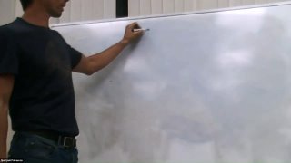 Кадр из видео: человек у большой белой доски в учебном классе, объясняет материал курса по теории яхтинга.