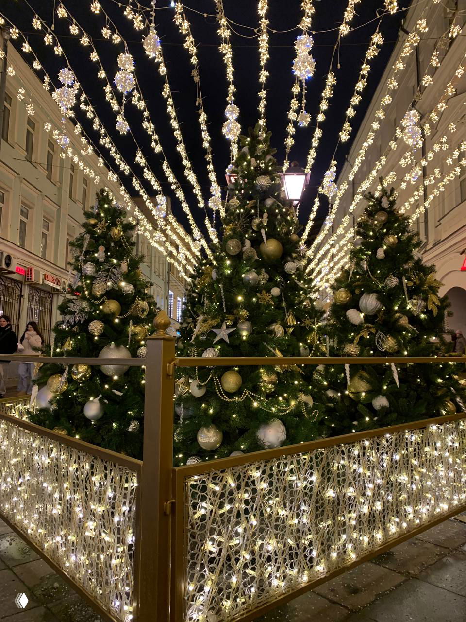 Большая декоративная фигура мышонка в короне на фоне освещённых елей и инсталляций, композиция создаёт сказочную атмосферу праздника.