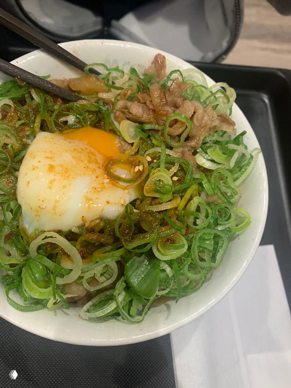 Миска риса с тонко нарезанным мясом, множеством зелёного лука и мягким яйцом сверху — типичный простой японский обед для местных.