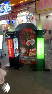 Ночная улица развлечений в Осаке с плотной концентрацией неоновых вывесок, крупной движущейся декоративной фигурой краба и витринами, привлекающими прохожих.