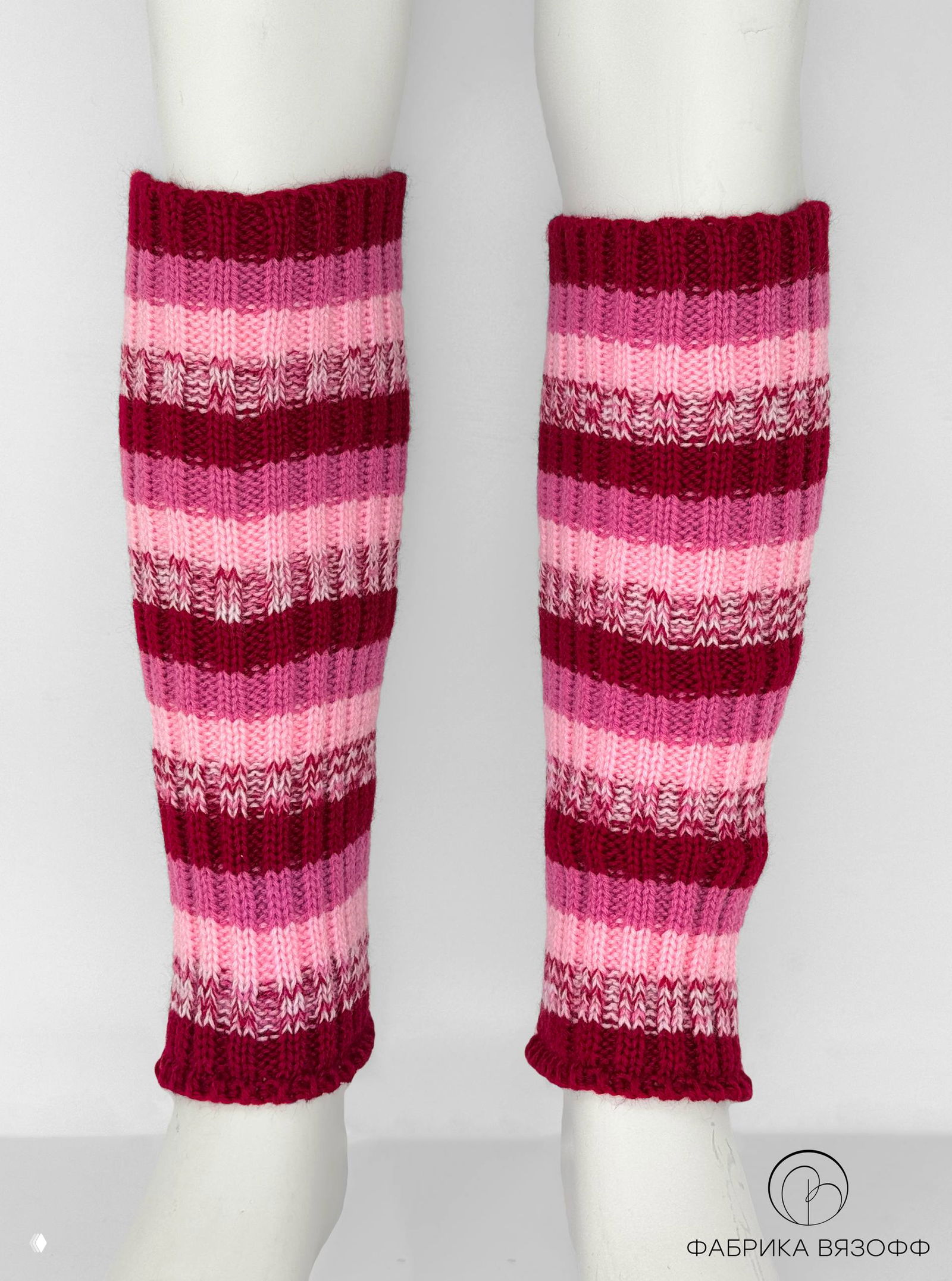 Пара розово‑бордовых гетр на манекенных ногах, вид в полный рост показывает длину изделия и соотношение полос, логотип производителя внизу.