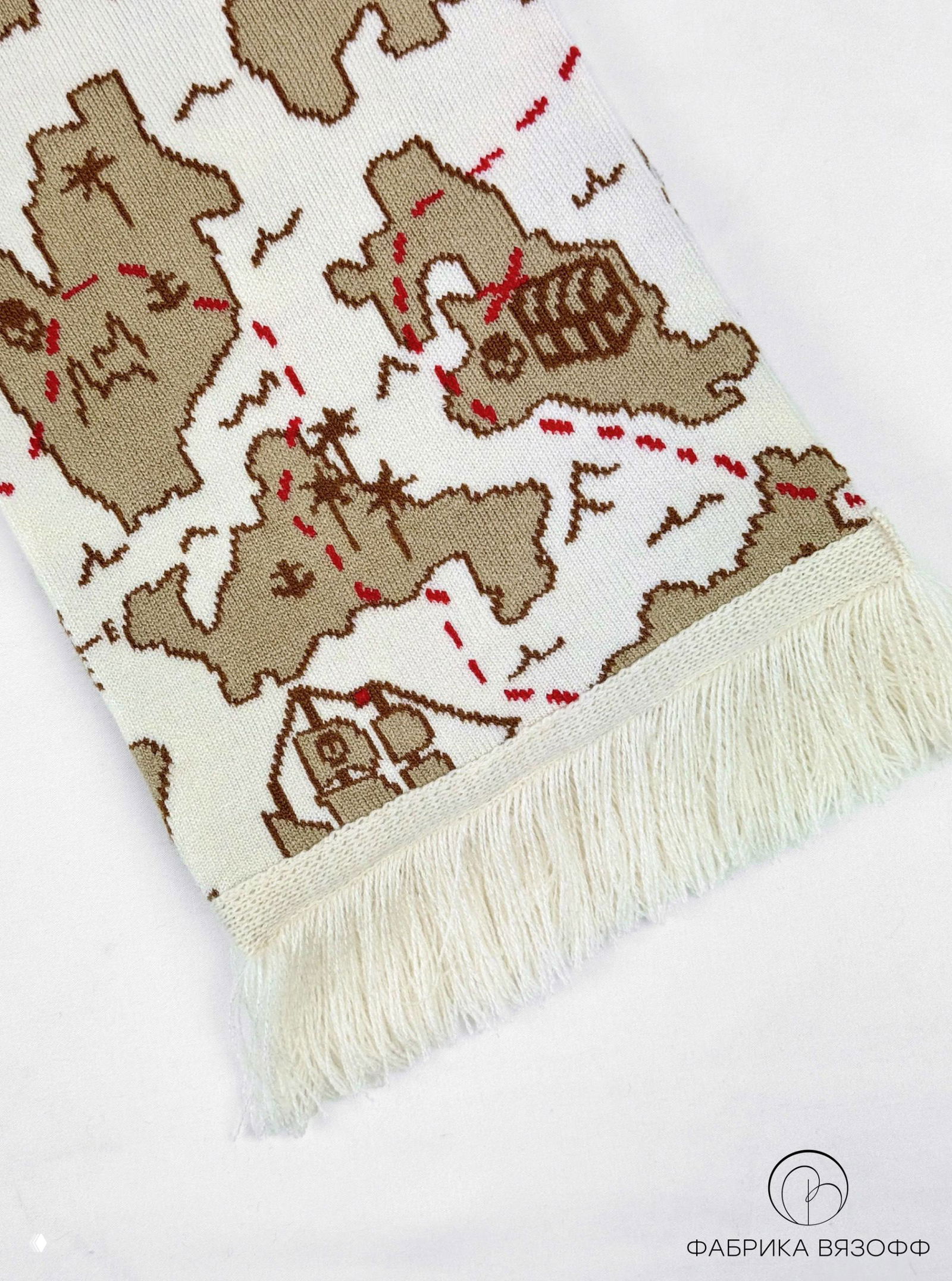 Крупный план края шарфа с бахромой; рисунок карты с островами, пальмами и пунктирными красными линиями, текстура вязки хорошо видна.