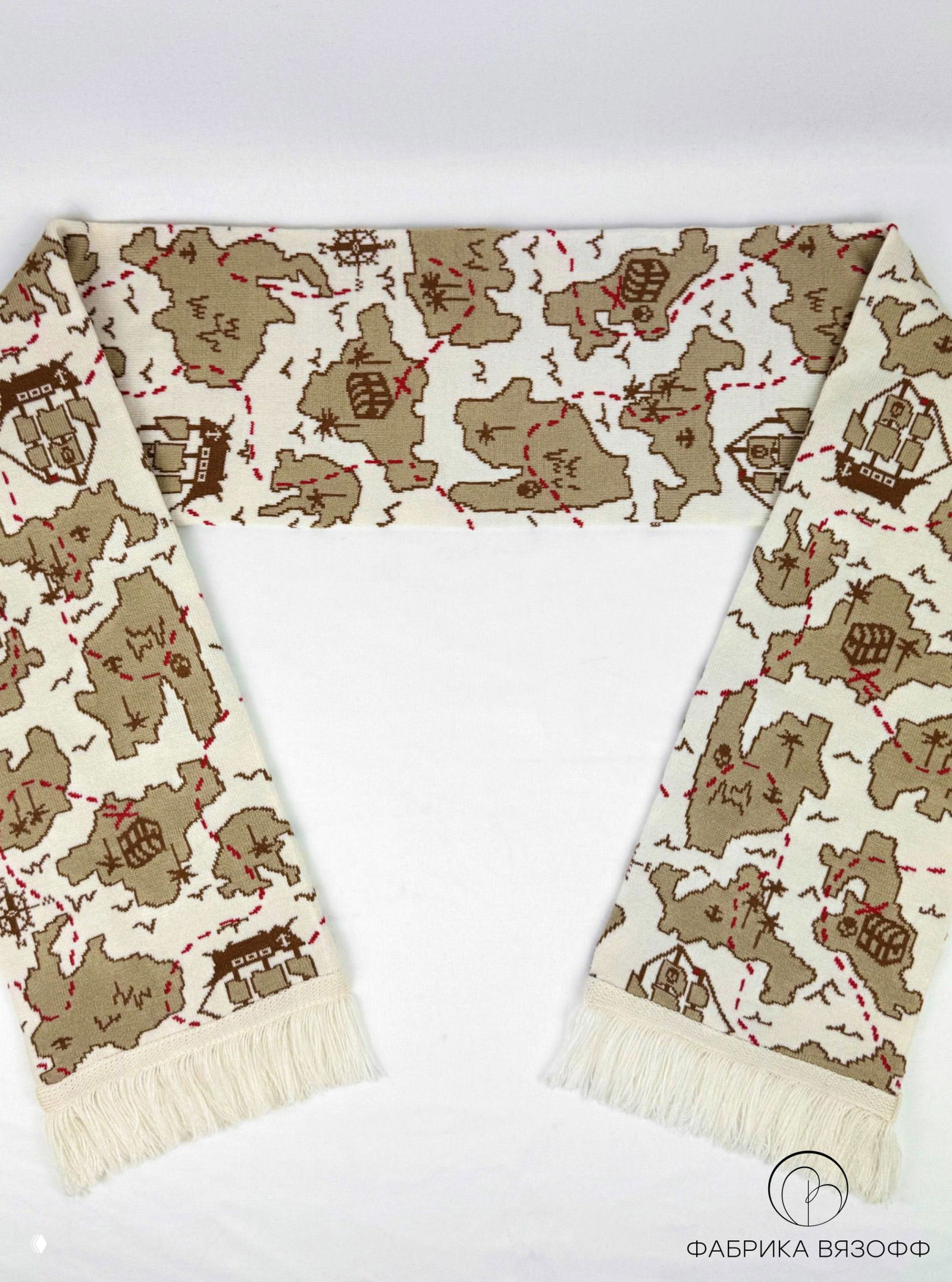 Шарф разложен полукругом: виден весь повторяющийся рисунок карты с островами, сундуком и пунктирной дорогой, аккуратная бахрома.