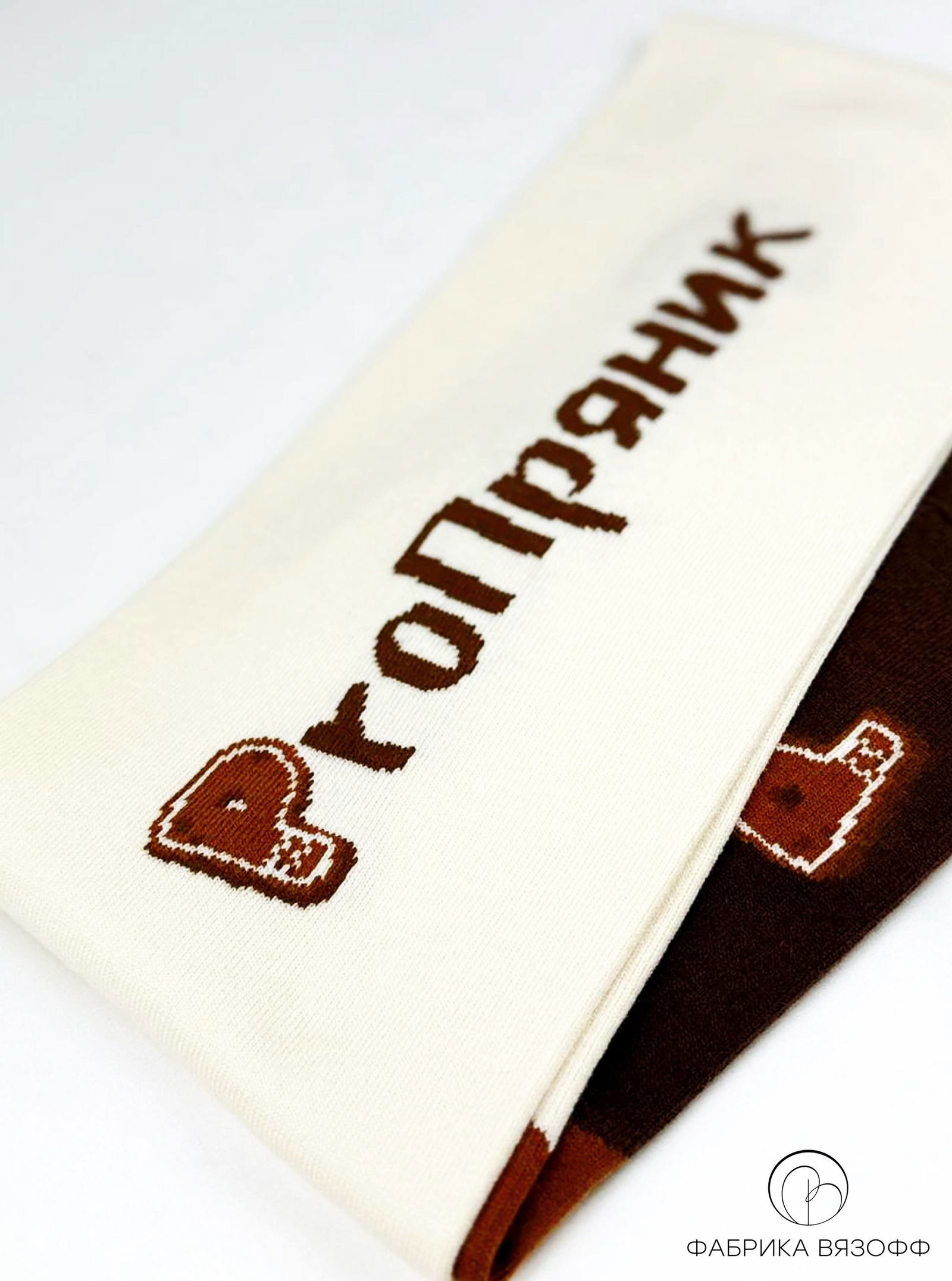 Повернутая часть шарфа с надписью «Пряник» (вязанный шрифт) на светлом фоне, видна плотность полотна и аккуратность вязаной графики.