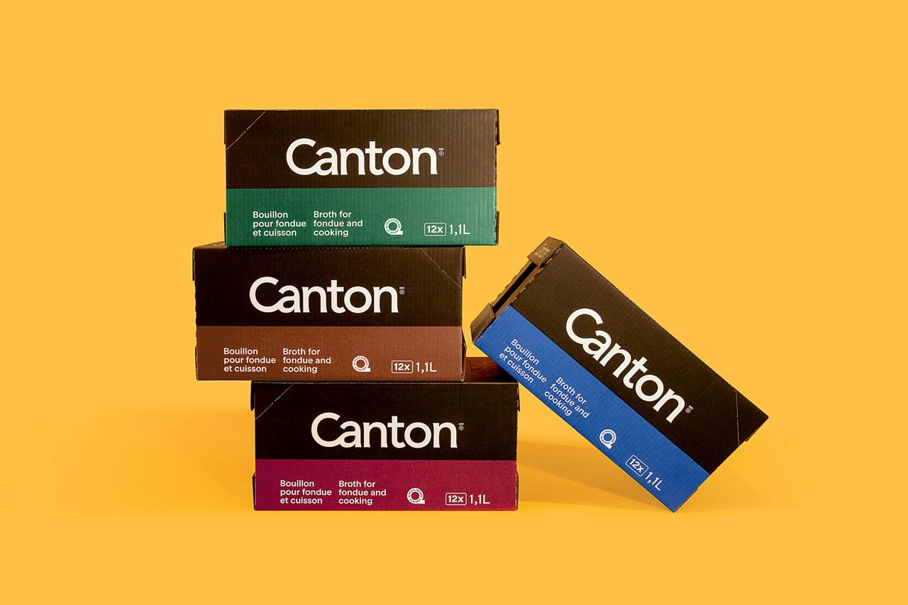 Фотография нескольких картонных коробок с логотипом Canton, сложенных на однотонном жёлтом фоне; вид акцентирует новую упаковку и шрифт.