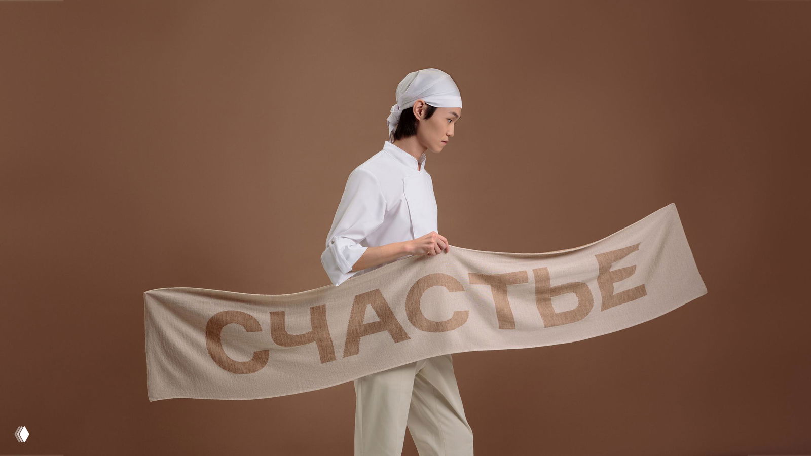 Руки наклеивают вертикальную белую наклейку с логотипом ILLAN COMMUNICATIONS на картонную коробку — упаковочный снимок кампании и детализация бумаги и поверхности.