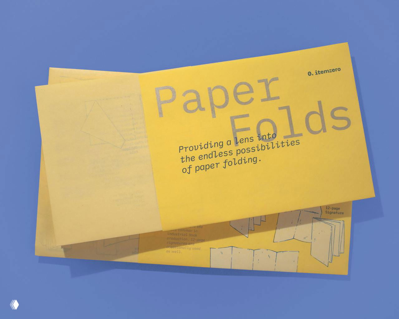Открытая желтая брошюра «Paper Folds» на синем фоне с диаграммами сгибов бумаги и крупным заголовком, демонстрация вариантов складывания.